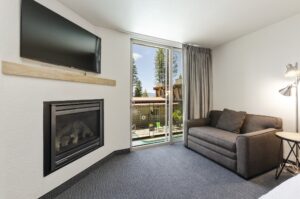 firelite lodge sofa and fireplace room sofa bed next to a window with a view of the pool at firelite lodge. a tv is above the mantel, which is above a gas fireplace