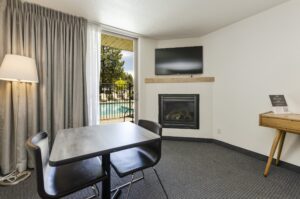 room with table and fireplace fireplace, tv, table and chairs inside a hotel room with a glass door out to the pool