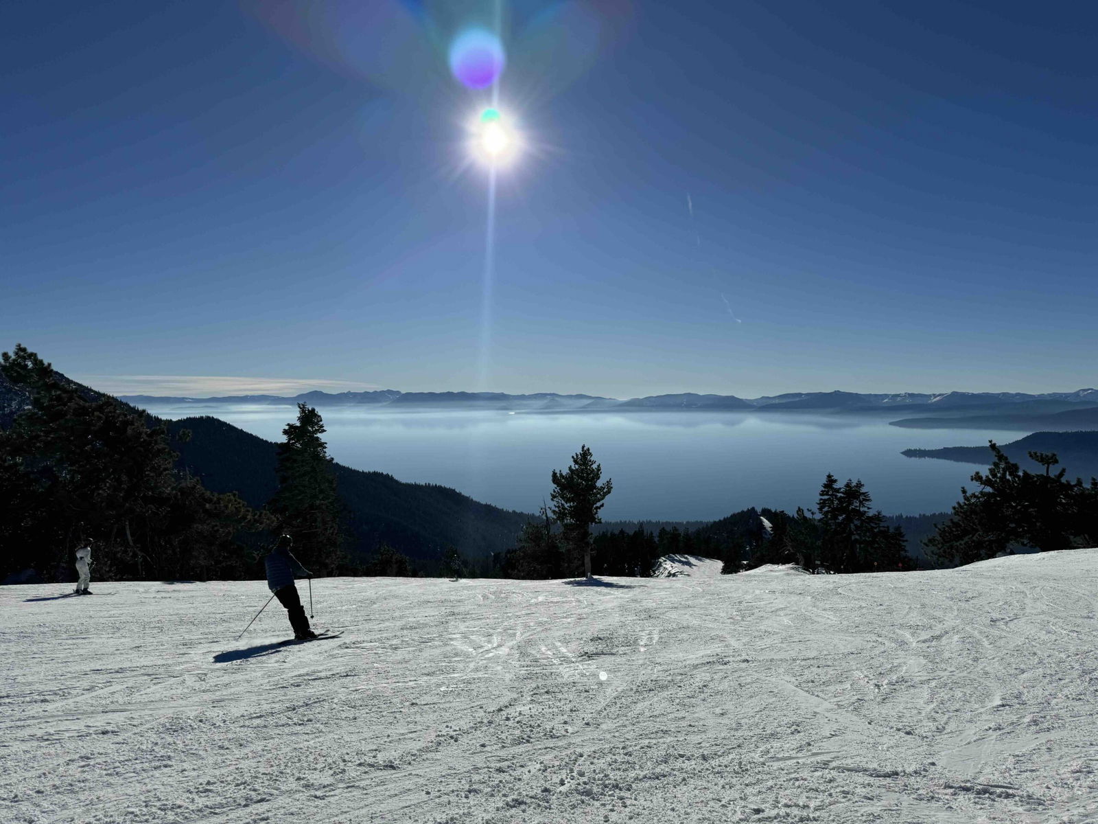 Skiing North Lake Tahoe with slopes, skiiers, and lake in the background with blue sky